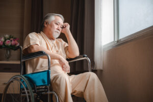 Senior male patient with grey hair and hospital clothing sitting on wheelchair
